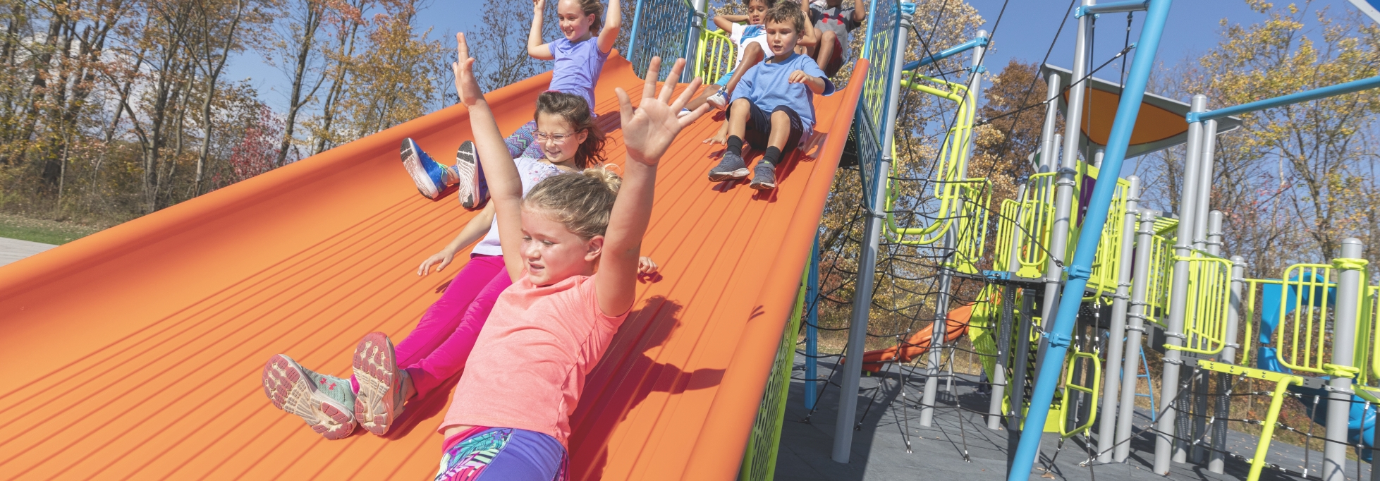 Children sliding down an orange slide.