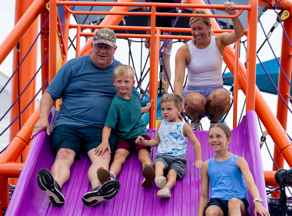 A family with three kids sliding down a Mighty Descent slide