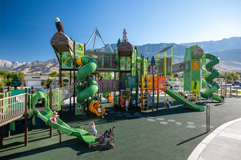 Cross-generational, multi-generational, inclusive families playing at an inclusive playground and park.
