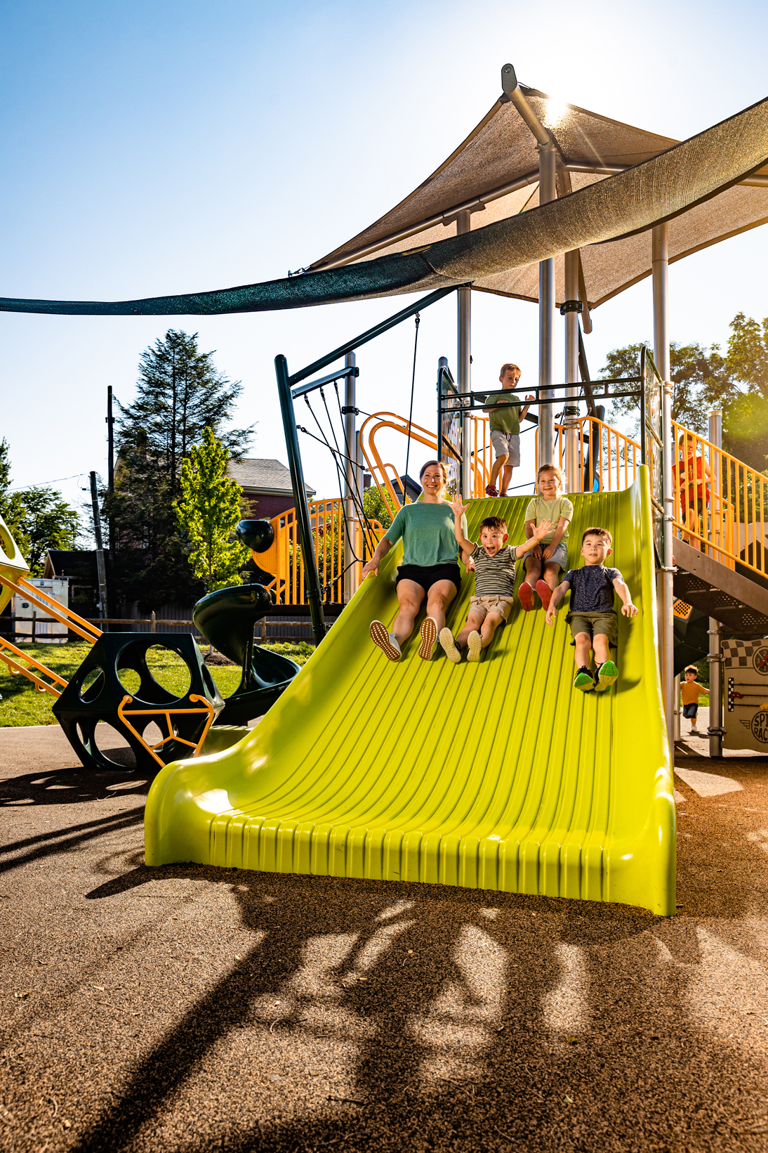 A mom and three boys sliding down a Mighty Descent slide