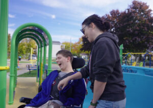 Person using a wheelchair and their caregiver having fun at Park of Hope in Canada