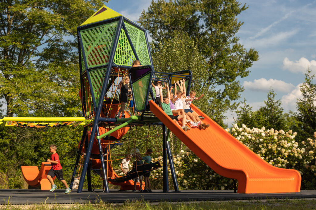 Children sliding down the Mighty Descent slide while other kids wait their turn