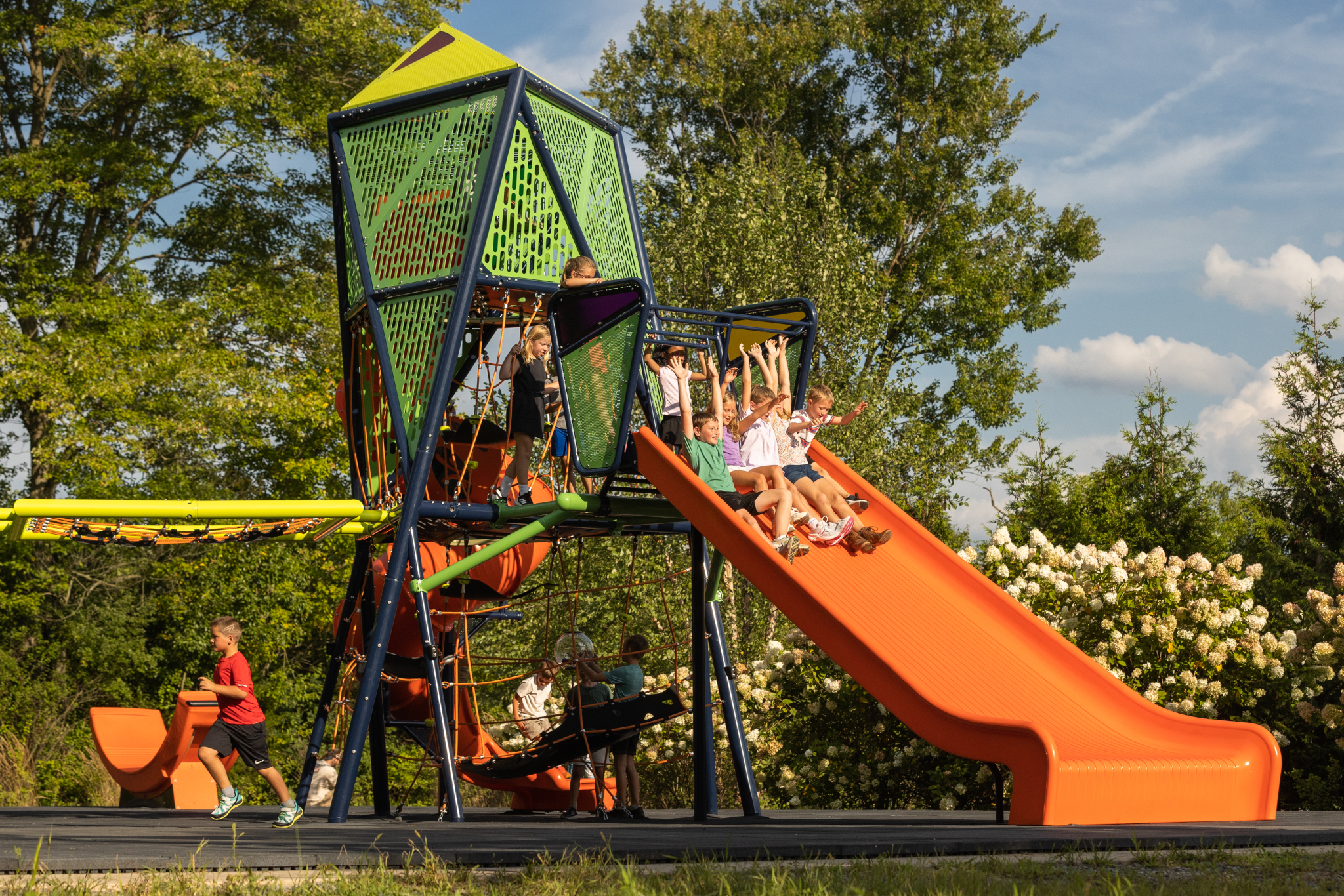 Children sliding down the Mighty Descent slide while other kids wait their turn
